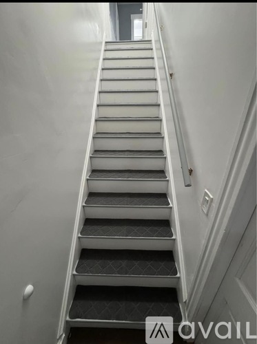 A staircase with a metal railing and a carpeted step.