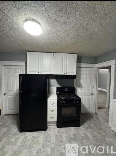 A black refrigerator and stove in a kitchen with white cabinets.
