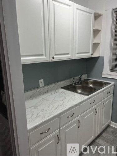 A kitchen with white cabinets and a marble countertop.