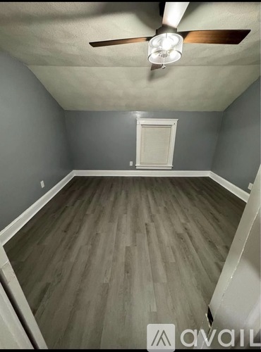 A room with a ceiling fan and wooden flooring.