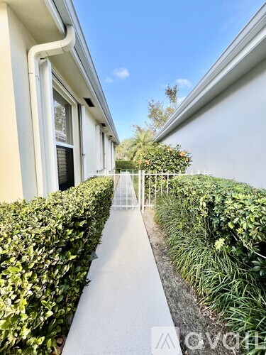 A white building with a hedge on the side.