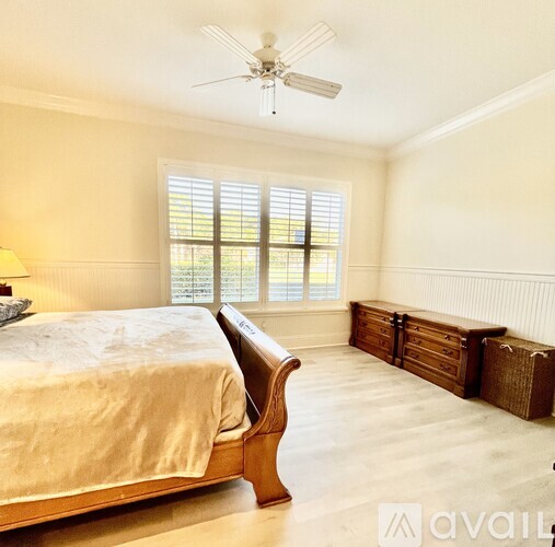 A bedroom with a large bed and a window with blinds.
