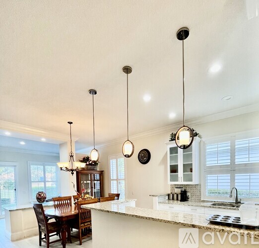 A kitchen with a table and chairs and pendant lights hanging from the ceiling.