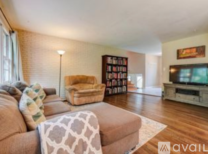 A living room with a couch, a chair, a bookshelf, and a television.