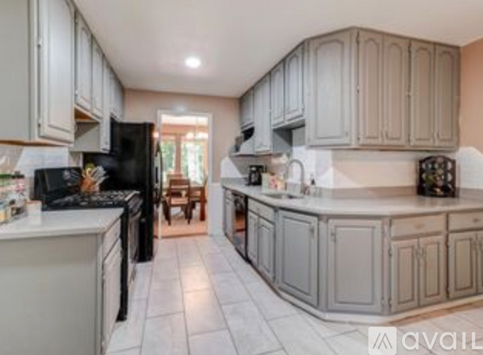 A kitchen with white cabinets and black appliances.