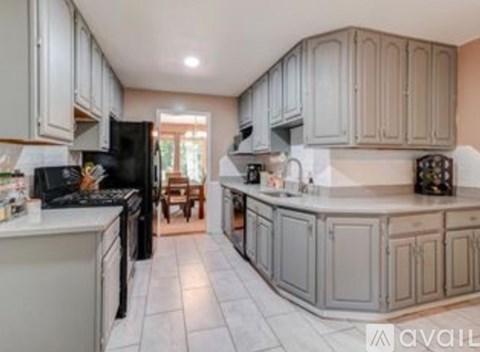 A kitchen with white cabinets and black appliances.