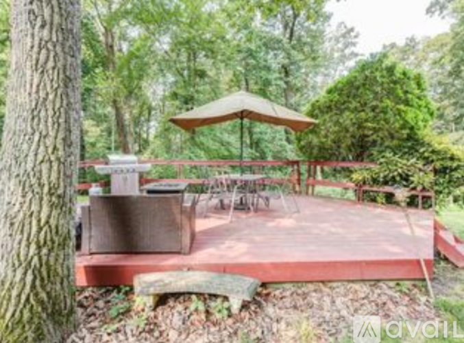 A wooden deck with a table and chairs is surrounded by trees.