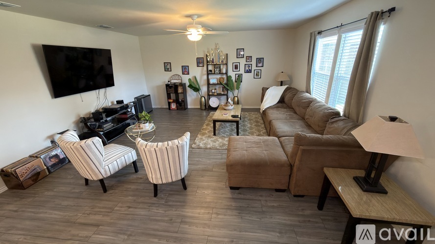 A living room with a brown sofa, striped armchair, and a television on the wall.