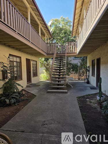 A wooden staircase leads up to a balcony on the second floor of a house.