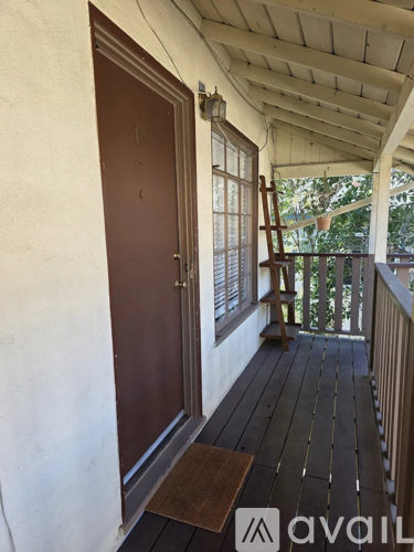 A brown door is on the left of a balcony with a cat tree.