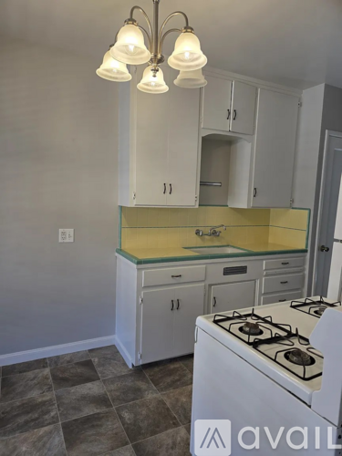 A kitchen with a white stove and cabinets.