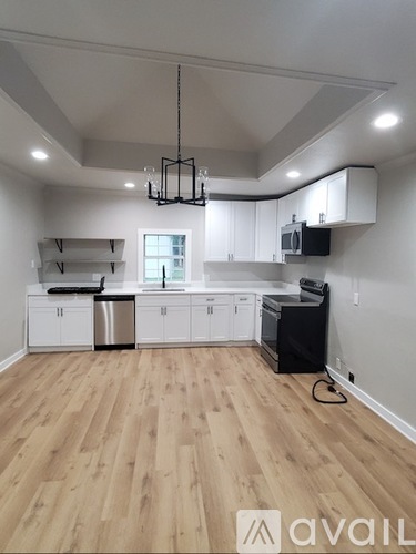 A kitchen with wooden floors and white cabinets.