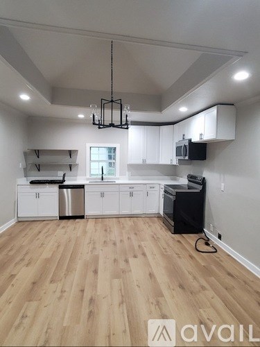 A kitchen with wooden floors and white cabinets.