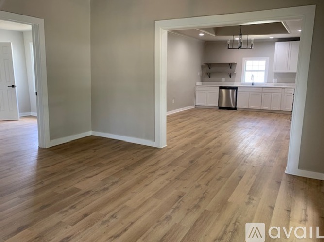 A spacious room with wooden flooring and white walls.