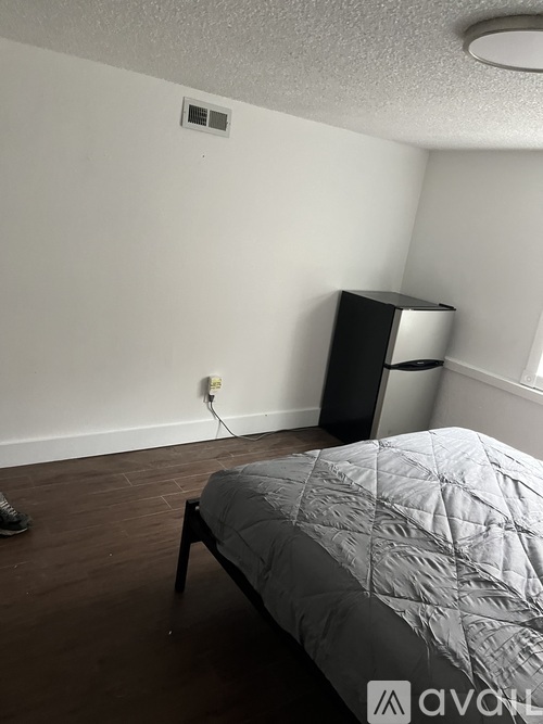 A bedroom with a bed, a nightstand, and a window.
