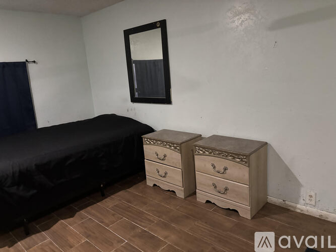 A bedroom with a bed, two drawers, and a mirror.