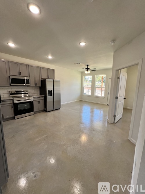 A spacious kitchen with stainless steel appliances and a ceiling fan.