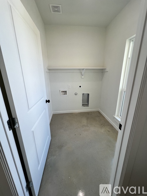 A small, empty room with a door on the left and a window on the right.