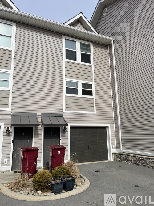 A house with a grey siding and a black garage door.