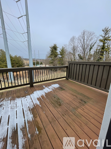 A wooden deck with a metal railing and a view of trees and a body of water.