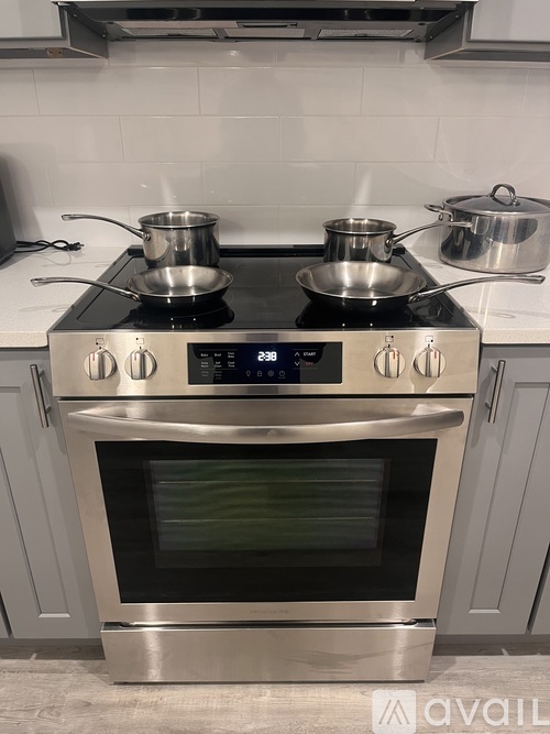 A stainless steel oven with four burners and a digital control panel is on a kitchen counter.