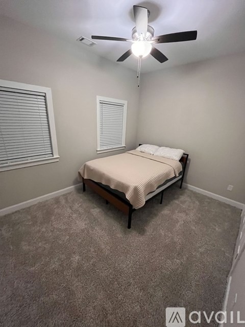 A bedroom with a bed, carpet, and a ceiling fan.