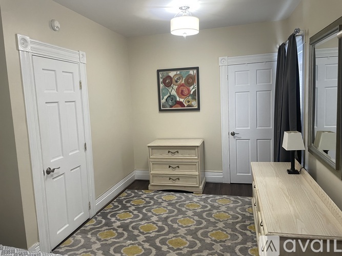 A bedroom with a patterned carpet and a wooden bench.