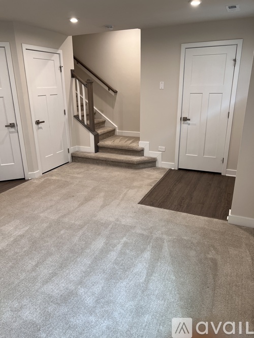 A hallway with a carpeted floor and a staircase.
