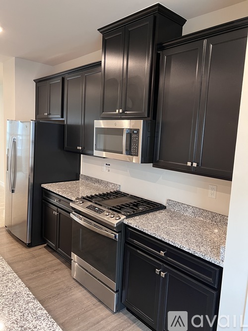 A kitchen with black cabinets and stainless steel appliances.