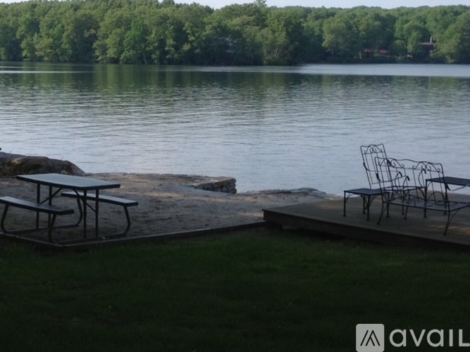 A picnic table and chairs are set up on a dock by a lake.