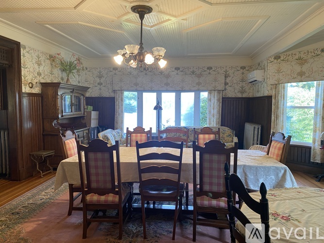 A dining room with a table set for six and chairs around it.