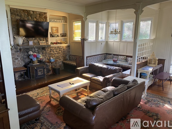 A living room with a stone fireplace and leather furniture.