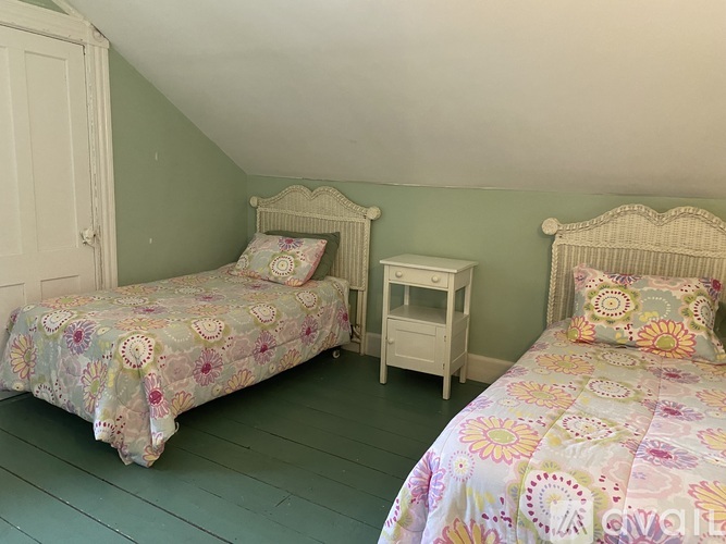 A bedroom with two beds and a nightstand.