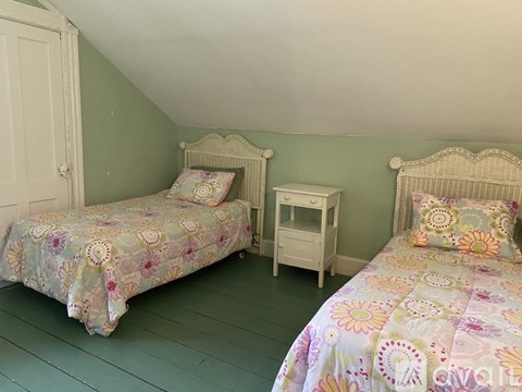 A bedroom with two beds and a nightstand.