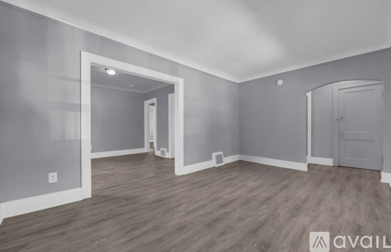 A spacious room with wooden flooring and white walls.