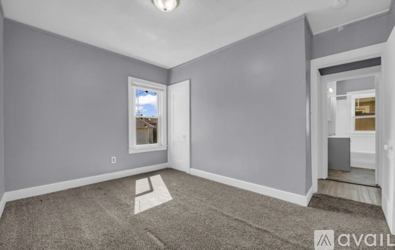 A room with grey walls and a window overlooking a building.