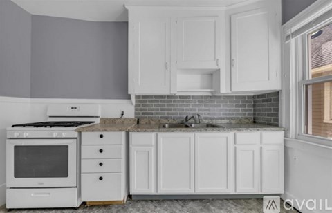 A kitchen with white cabinets and a brick backsplash.