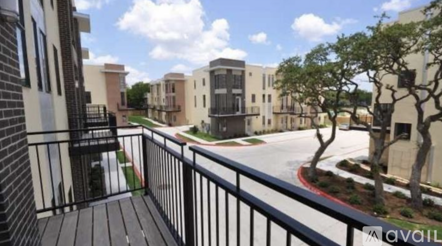 A balcony overlooks a courtyard with trees and buildings.