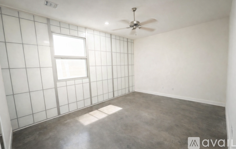 A room with a ceiling fan and a window with tiled walls.