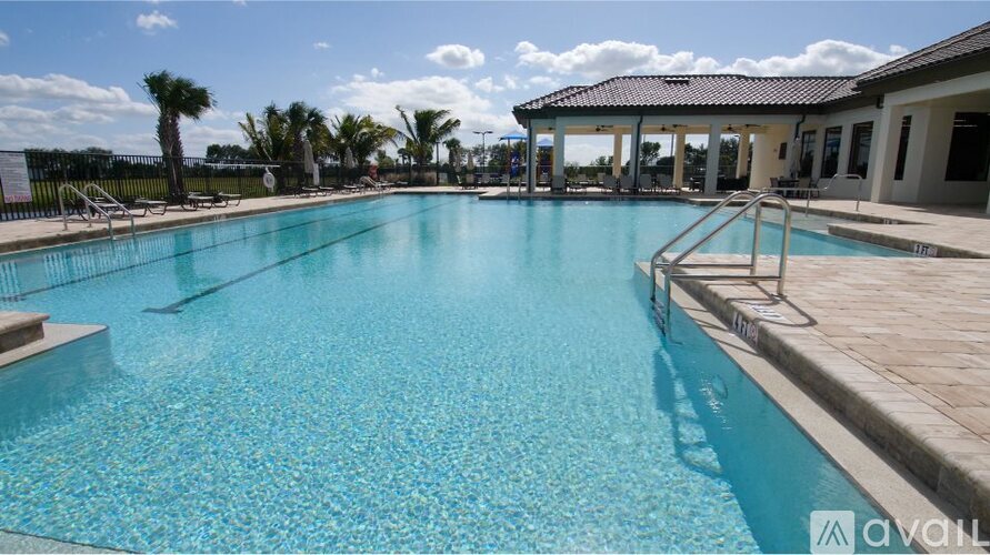 A large outdoor swimming pool with a tiled edge and a metal ladder on the right side.