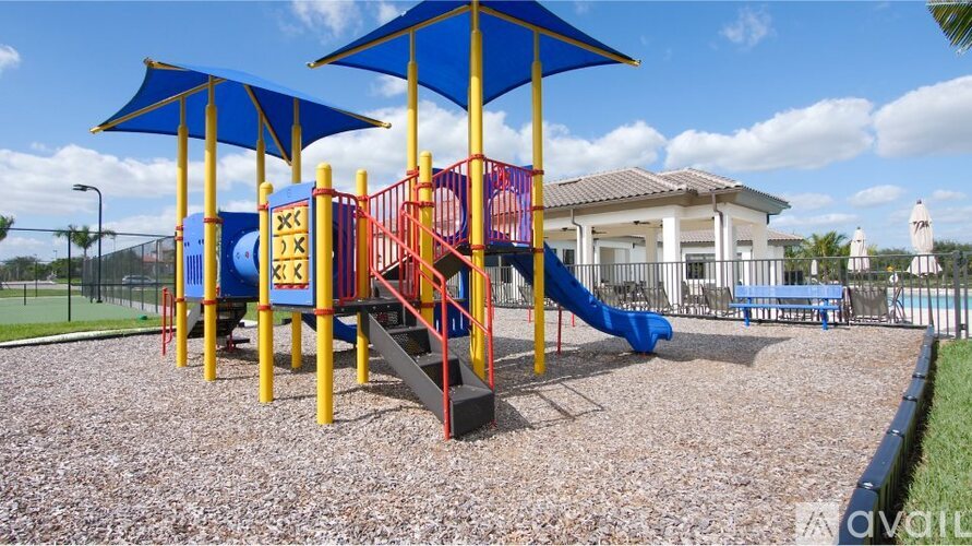 A playground with a blue umbrella and a yellow slide.