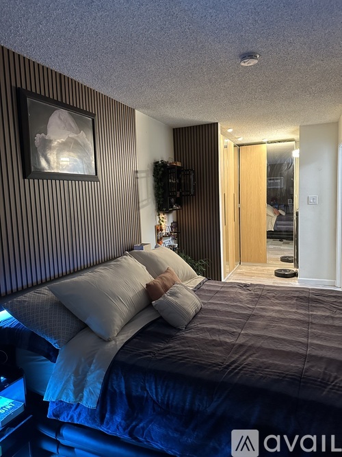 A bedroom with a bed, a picture on the wall, and a door leading to another room.