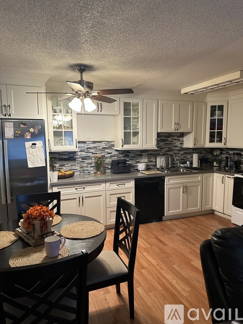A kitchen with a table and chairs in the foreground and a refrigerator in the background.