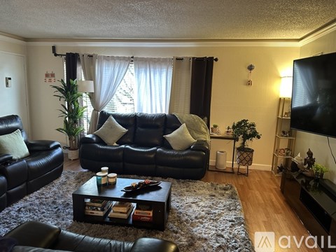 A living room with a black leather couch and a coffee table.