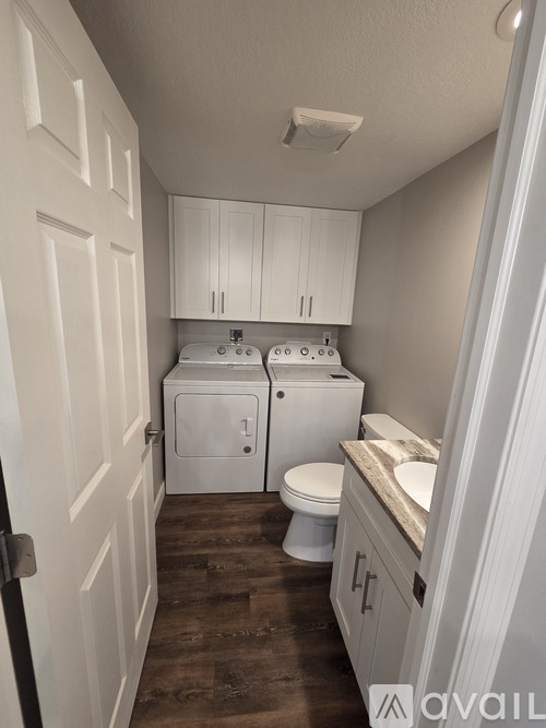 A small bathroom with a toilet, sink, and cabinets.