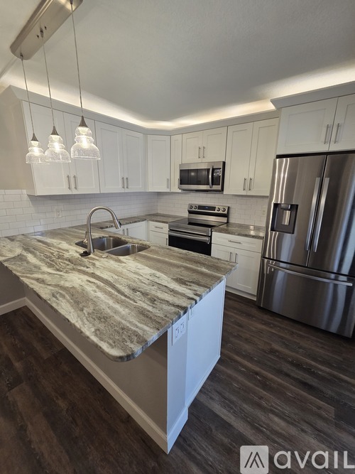 A kitchen with a marble countertop and stainless steel appliances.