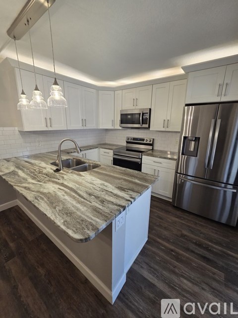 A kitchen with a marble countertop and stainless steel appliances.