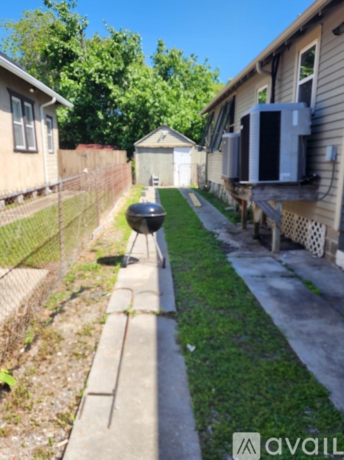 A small alley with a fence and a house with a large air conditioner unit.