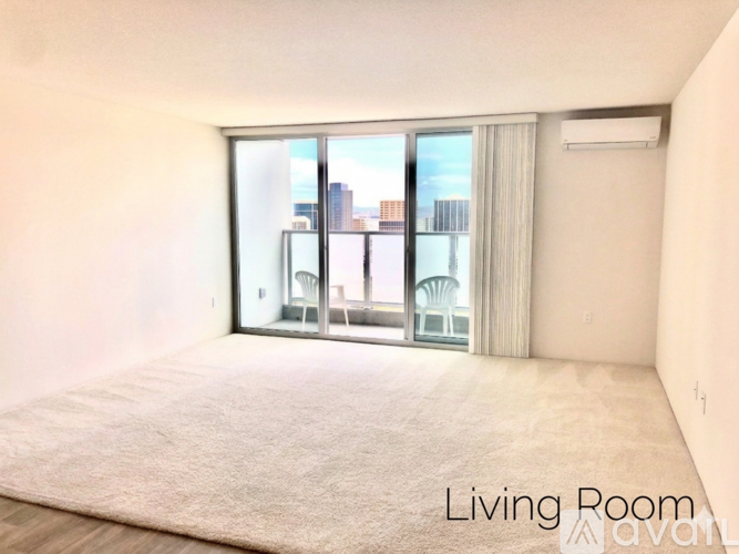 A living room with a carpet and a window overlooking a cityscape.