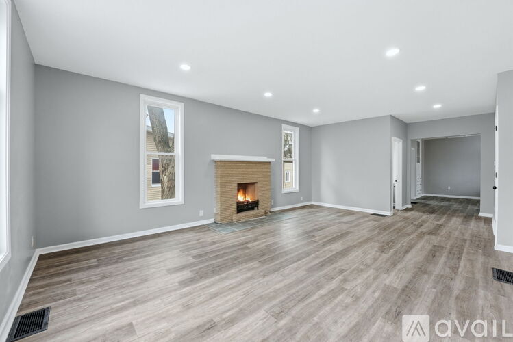 A spacious living room with a fireplace and a painting on the wall.
